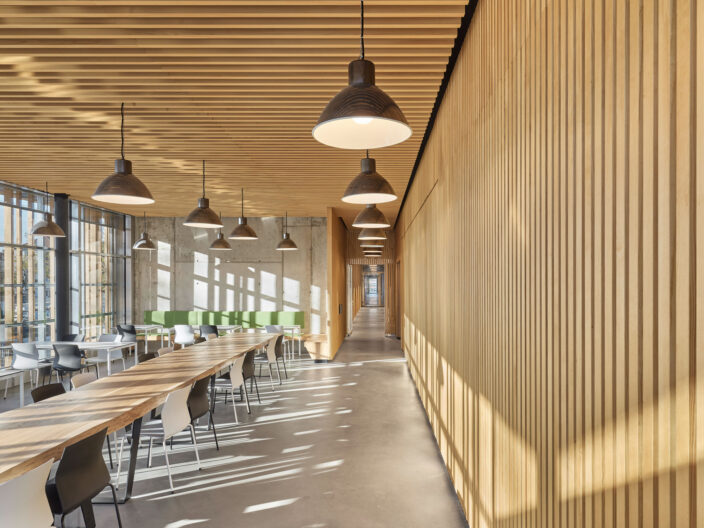 Innenraumperspektive lichtdurchflutete Cafeteria mit Holzlamellenwänden der Neugestaltung Betriebsstandort Deckerstraße