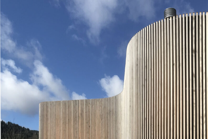 Außenperspektive der geschwungenen Holz-Fassade des Neubaus Energiezentrale Schönau